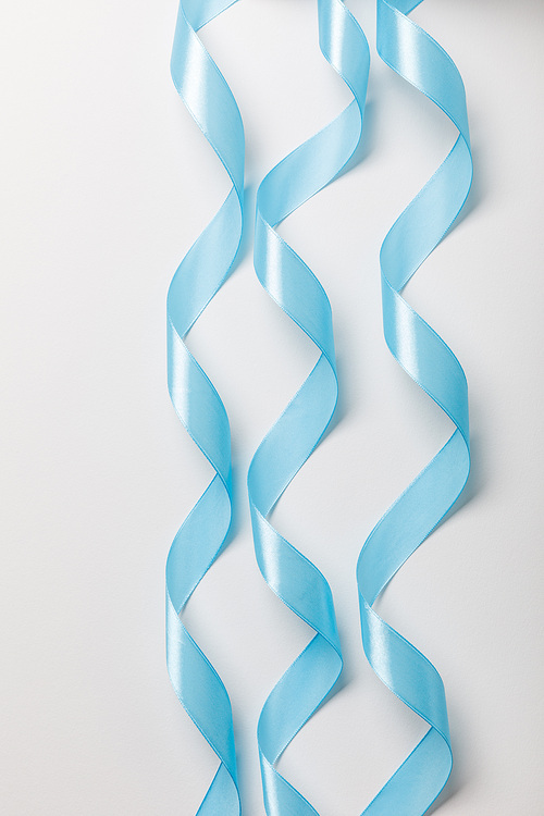 top view of blue wavy silk ribbons on grey background