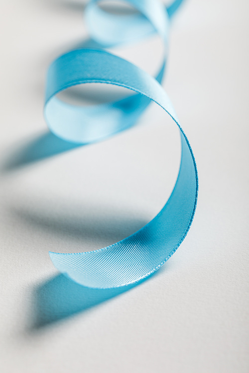 close up of curved blue satin ribbon on grey background
