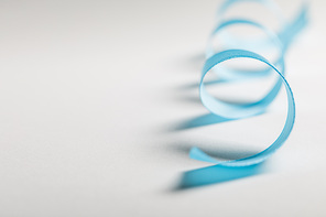 close up of curved blue satin ribbon on grey background with copy space