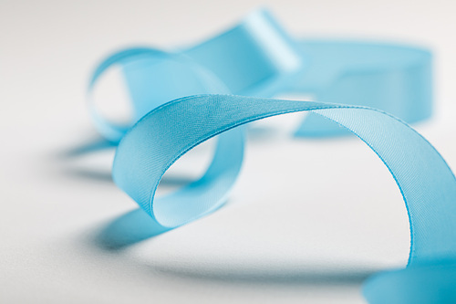 close up of wavy blue satin ribbon on grey background