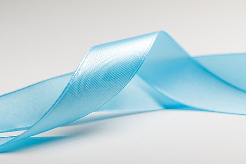 close up of curved blue silk ribbon on grey background