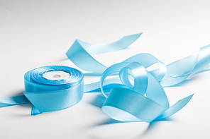 curved blue satin ribbon with spool on grey background
