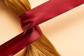 Top view of brown hair with ribbon on beige background