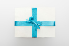 top view of blank card with blue decorative satin ribbon and bow on white background
