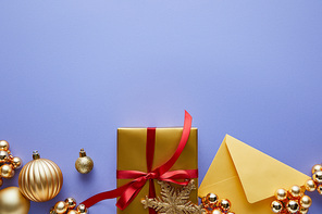 top view of shiny golden Christmas decoration, envelope and gift box on blue background