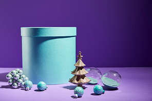 blue gift box and decorative Christmas tree with baubles on purple background