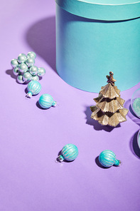 blue gift box and decorative Christmas tree with baubles on violet background