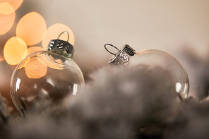 transparent christmas balls on spruce branches in snow with yellow lights bokeh