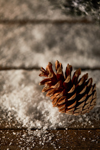 close up of pine cone on wooden table with snow on christmas