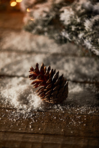 pine cone on wooden table with spruce branches and snow on christmas
