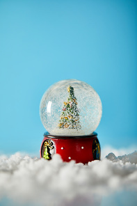 christmas tree in snowball standing on blue with snow