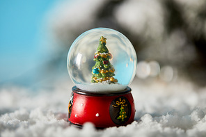 christmas tree in decorative snowball standing on blue with snow