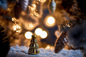 close up of christmas tree with decorative christmas balls on snow with lights bokeh at night