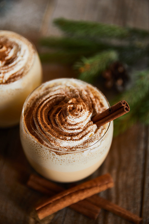 close up view of delicious eggnog cocktail with whipped cream and cinnamon on wooden table