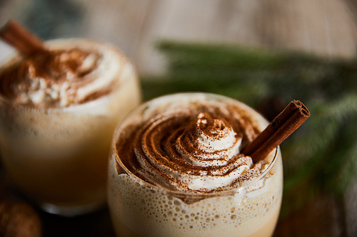 close up view of traditional eggnog cocktail with whipped cream and cinnamon on wooden table