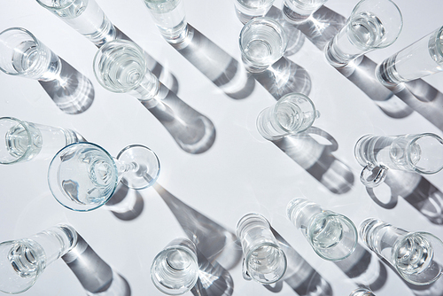 top view of transparent glasses with clear water on white background with shadows