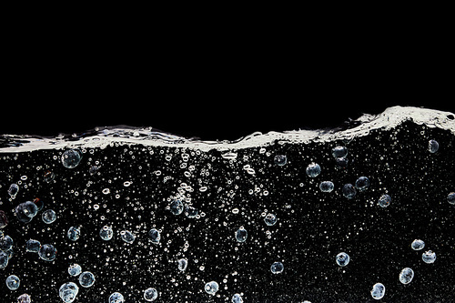 ripe blueberries deep in water with bubbles isolated on black