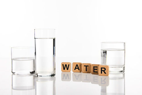 clear fresh water in glasses near cubes with water lettering isolated on white
