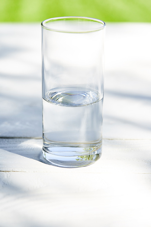 fresh clean water in transparent glass at sunny day on wooden table