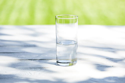 fresh clean water in transparent glass at sunny day on wooden table