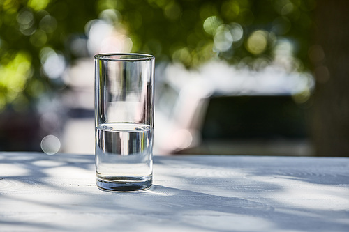 fresh clean water in transparent glass at sunny day outside on wooden table