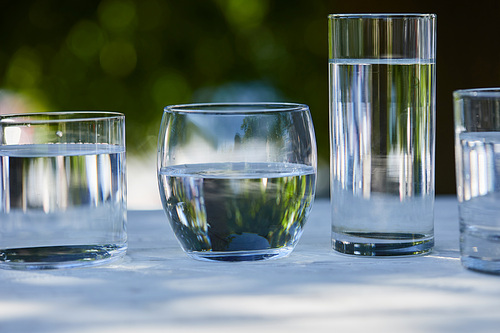 clear fresh water in transparent glasses in sunlight on wooden table