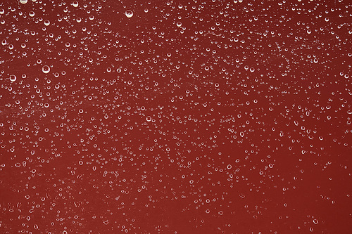 clear transparent water drops on red background