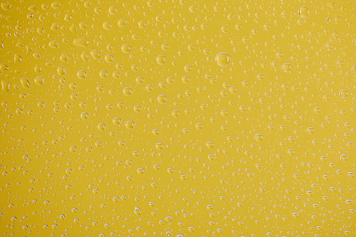 clear transparent water drops on yellow background