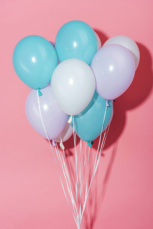 white, blue and purple decorative festive balloons with shadow on pink background