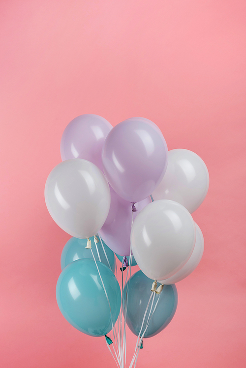white, blue and purple festive balloons on pink background