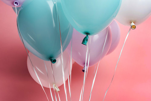 close up view of white, blue and purple balloons on pink background