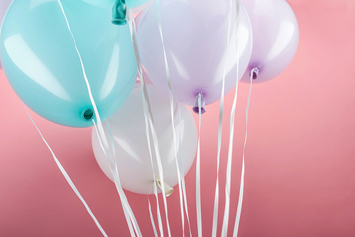 close up view of blue, white and purple colorful balloons on pink background