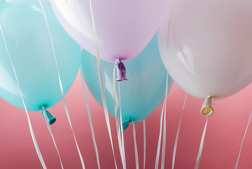 close up view of blue, white and purple balloons on pink background