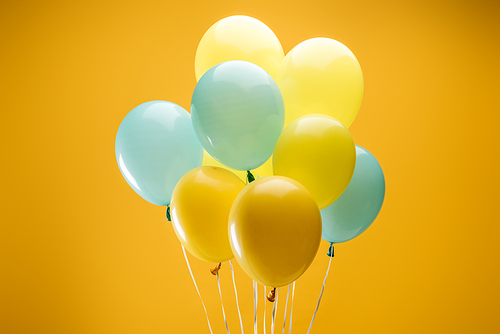 festive bright blue and yellow balloons on yellow background