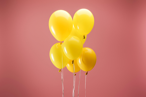 yellow festive balloons on pink background, party decoration