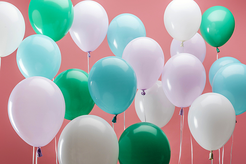 bright green, white and blue decorative balloons on pink background