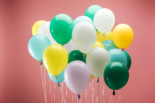 bright green, yellow, white and blue decorative balloons on pink background