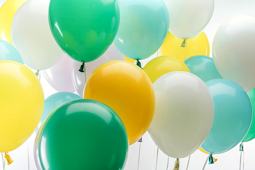 close up view of bright green, yellow and blue decorative balloons on white background