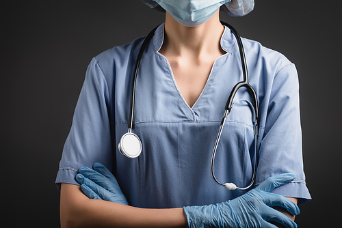 cropped view of nurse in medical mask and latex gloves standing with crossed arms isolated on dark grey