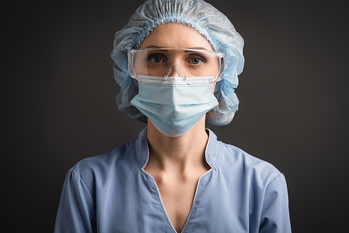 nurse in medical cap, mask and goggles  isolated on dark grey