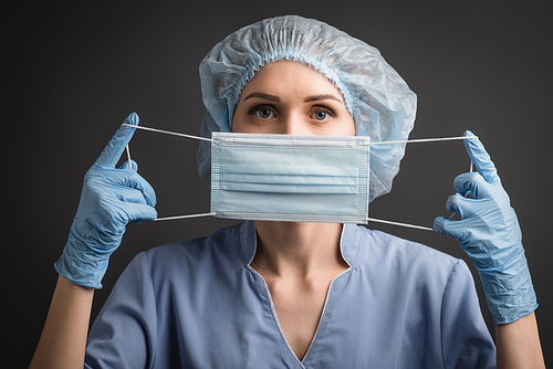 nurse in latex gloves wearing medical mask isolated on dark grey