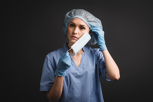 nurse in medical cap wearing mask isolated on dark grey