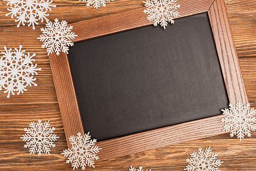 top view of winter snowflakes on chalkboard on wooden background