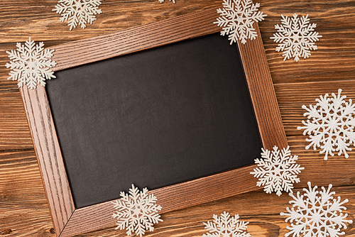 top view of winter snowflakes on chalkboard on wooden background