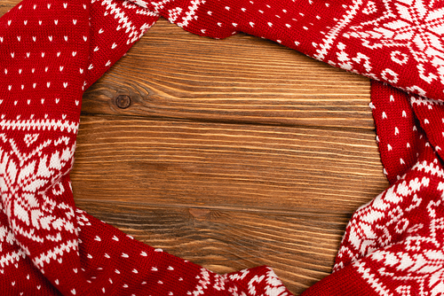 top view of winter red knitted scarf on wooden background