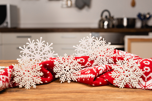 winter snowflakes and knitted red scarf on wooden table