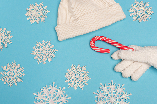 top view of winter white knitwear, candy cane and snowflakes on blue background