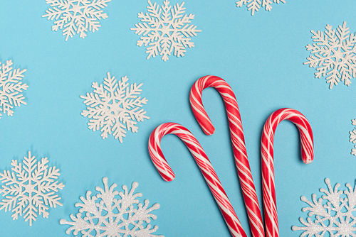 top view of candy cane and snowflakes on blue background