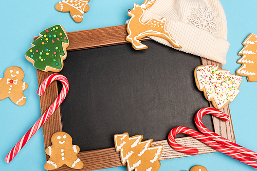top view of gingerbread cookies and chalkboard on blue background