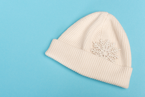 top view of white beanie and snowflake on blue background
